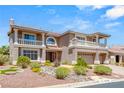 A two-story home with a beige stucco exterior, two balconies, a three-car garage, and desert landscaping at 4542 Grey Spencer Dr, Las Vegas, NV 89141