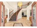 Grand foyer showcases a sweeping staircase, tiled floors, and elegant chandelier at 4542 Grey Spencer Dr, Las Vegas, NV 89141
