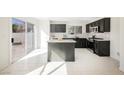 Modern kitchen featuring dark cabinetry, a central island, stainless steel appliances, and sliding doors leading to the backyard at 5357 Hammond Ct, Las Vegas, NV 89110