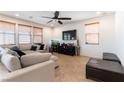 Spacious living room with a plush sectional sofa, modern ceiling fan, and ample natural light from multiple windows at 10355 Sipple St, Las Vegas, NV 89141