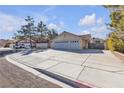 Street view of a desert home featuring mature landscaping and a large driveway at 1709 Guthrie Dr, Las Vegas, NV 89117