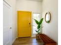 Bright entryway showcasing a yellow front door, wood floors, a plant, and a padded bench at 306 Rodarte St, Henderson, NV 89014