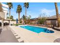 Backyard pool area with a sparkling pool, surrounding lounge area and well-manicured landscaping with tall palm trees at 5968 Saint Lazare St, Las Vegas, NV 89130