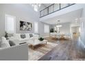 Bright living room featuring a two-story ceiling, hardwood floors, large windows, and an open floor plan to the dining area at 12279 Lost Treasure Ave, Las Vegas, NV 89138