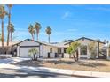 Charming single-story home with a two-car garage, desert landscaping, and palm trees at 2415 La Estrella St, Henderson, NV 89014