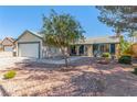 Inviting front yard with desert landscaping, mature trees, and a charming single-story home with a two-car garage at 3730 Greenwood Dr, Las Vegas, NV 89103