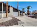 View of a one-story home with desert landscaping, a carport, an attached garage, and a long driveway at 3998 Foxgrove Dr, Las Vegas, NV 89147