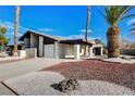 View of a one-story home with desert landscaping, a carport, an attached garage, and a long driveway at 3998 Foxgrove Dr, Las Vegas, NV 89147