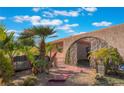 Close up of the home's front yard featuring a gated entrance, desert landscaping, and mature palms at 5385 Ravendale Cir, Las Vegas, NV 89120