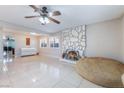 Bright living room featuring tile floors, a stone fireplace, and large windows with plantation shutters at 5385 Ravendale Cir, Las Vegas, NV 89120