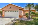 Home's facade featuring a two-car garage, desert landscaping, and a well-maintained lawn at 5452 Green Palms St, Las Vegas, NV 89130