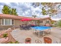 Spacious backyard featuring an outdoor dining area, ping pong table, and lush greenery, perfect for entertaining guests at 5990 Mcleod Dr, Las Vegas, NV 89120