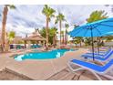 Backyard swimming pool and spa surrounded by lush landscaping, lounge chairs, and a covered outdoor kitchen and dining area at 5990 Mcleod Dr, Las Vegas, NV 89120