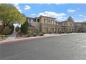 Multi-story townhouse with stone accents, tan exterior, well-manicured landscaping, and a two-car garage at 704 Peachy Canyon Cir # 101, Las Vegas, NV 89144