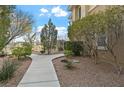 Lush front yard featuring manicured bushes, rock beds, and a winding sidewalk leading to the home at 704 Peachy Canyon Cir # 101, Las Vegas, NV 89144