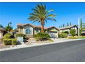 Well-maintained single-story home with lush landscaping, palm tree, and convenient two-car garage at 77 Chapman Heights St, Las Vegas, NV 89138