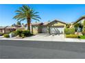 Charming single-story home featuring a lush green lawn, mature palm tree, and a two-car garage at 77 Chapman Heights St, Las Vegas, NV 89138