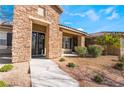 Charming front entrance with stone facade, a double-door entryway and drought-resistant landscaping, creating a warm welcome at 7860 Thunder Echo St, Las Vegas, NV 89131