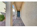 Entrance to home with brick walkway and steps and a teal front door and light stucco at 7870 Formitch Ct, Las Vegas, NV 89166