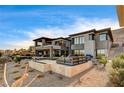 Stunning two-story home with an inviting patio, outdoor furniture and lush landscaping at 11296 Villa Bellagio Dr, Las Vegas, NV 89141