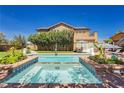 This backyard pool features a baja step entry, meticulous landscaping, and patio seating for relaxation at 6391 Tempting Choice Ave, Las Vegas, NV 89131