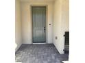 Welcoming front entrance with a modern gray-green door, brick flooring, and smooth stucco walls at 11443 Ethereal Landing Ave, Las Vegas, NV 89138