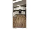 Bright kitchen featuring white cabinets, stainless steel appliances, and stylish wood-look flooring at 1640 E Kearney St, Pahrump, NV 89048