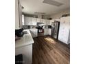 Bright kitchen featuring white cabinets, stainless steel appliances, and stylish wood-look flooring at 1640 E Kearney St, Pahrump, NV 89048