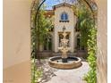 Charming courtyard featuring a decorative fountain, mature trees, and lush greenery creating a serene outdoor space at 2600 Cervino Cir, Henderson, NV 89052