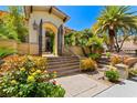 Stunning front entrance showcasing an arched gateway, stone steps, and lush landscaping for a grand arrival at 2600 Cervino Cir, Henderson, NV 89052