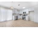 Bright kitchen featuring white cabinets, stainless steel appliances, and modern light fixture above sliding glass door at 1105 Pawnee Ln, Henderson, NV 89015