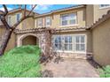 Townhome exterior showcases a stone archway, tiled roof, and manicured shrubbery, complemented by a brick pathway at 3064 Bicentennial Pkwy, Henderson, NV 89044