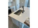 Close-up of a kitchen island featuring quartz countertops and stainless steel sink with matte black fixtures at 4540 Anspach St, North Las Vegas, NV 89031