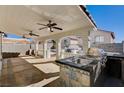 Spacious covered patio with outdoor kitchen, including stainless steel sink and built-in grill under ceiling fans at 4839 Englewood Ave, Las Vegas, NV 89139