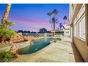 Backyard pool and spa area with mature palm trees and outdoor seating at dusk at 62 Incline Village Ct, Henderson, NV 89074