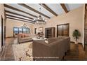 Spacious living room with wood beam ceilings, hardwood floors, a decorative chandelier and neutral-colored furniture at 6760 Hinson St, Las Vegas, NV 89118