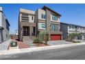 Contemporary home with a red two-car garage, stone accents, and landscaped front yard at 7180 Grace Estate Ave, Las Vegas, NV 89113