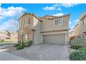 Charming two-story home boasts a neutral paint, desert landscaping, and a paver driveway leading to a two-car garage at 7707 W Diablo Dr, Las Vegas, NV 89113