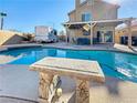 A refreshing backyard pool with a stone bench and a covered patio for outdoor entertaining at 1508 Splinter Rock Way, North Las Vegas, NV 89031