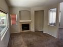 Spacious living room featuring plush carpet, a cozy fireplace, and large windows for ample natural light at 3337 Autumn Veil St, Las Vegas, NV 89129