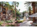 Resort-style pool area with rock waterfall feature and lush tropical landscaping at 7123 S Durango Dr # 206, Las Vegas, NV 89113