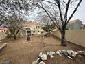 Expansive backyard with desert landscaping, a pergola-covered patio, and mature trees at 7509 Wheat Grass Ct, Las Vegas, NV 89129