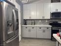 Updated kitchen with gray cabinets, white upper cabinets, stainless steel appliances, and gray subway tile backsplash at 807 Zinnia Cir, Henderson, NV 89015