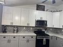 Bright kitchen with stainless steel appliances, white upper cabinets, and gray lower cabinets, completed with gray backsplash at 807 Zinnia Cir, Henderson, NV 89015