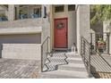 Close-up of home's entrance showing a red door with a wreath, metal railings, and stone steps at 10393 Rose Palisade St, Las Vegas, NV 89141
