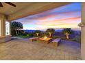 Relaxing covered patio with stone floors, a cozy fire pit, seating, and views of the sunset at 2869 Josephine Dr, Henderson, NV 89044