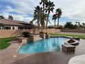 Inviting backyard pool area with mature palms, artificial turf, and stamped concrete surround at 6392 Ebony Legends Ave, Las Vegas, NV 89131