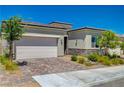 Charming single-story home featuring a two-car garage, brick driveway, stone accents and landscaped front yard at 8525 Stokestone St, Las Vegas, NV 89166