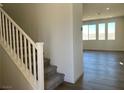 Modern entryway with carpeted stairs, white railings, and wood-look flooring leading to a bright living area at 10012 River Corral St, Las Vegas, NV 89166