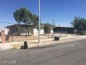 Well-kept single-story home with a gravel front yard, mature trees, and chain-link fence at 2705 Howard Dr, Las Vegas, NV 89104